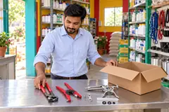A dealer lays out a hoof nipper, an ear tag applicator and a dosing syringe beside an open carton of new stock